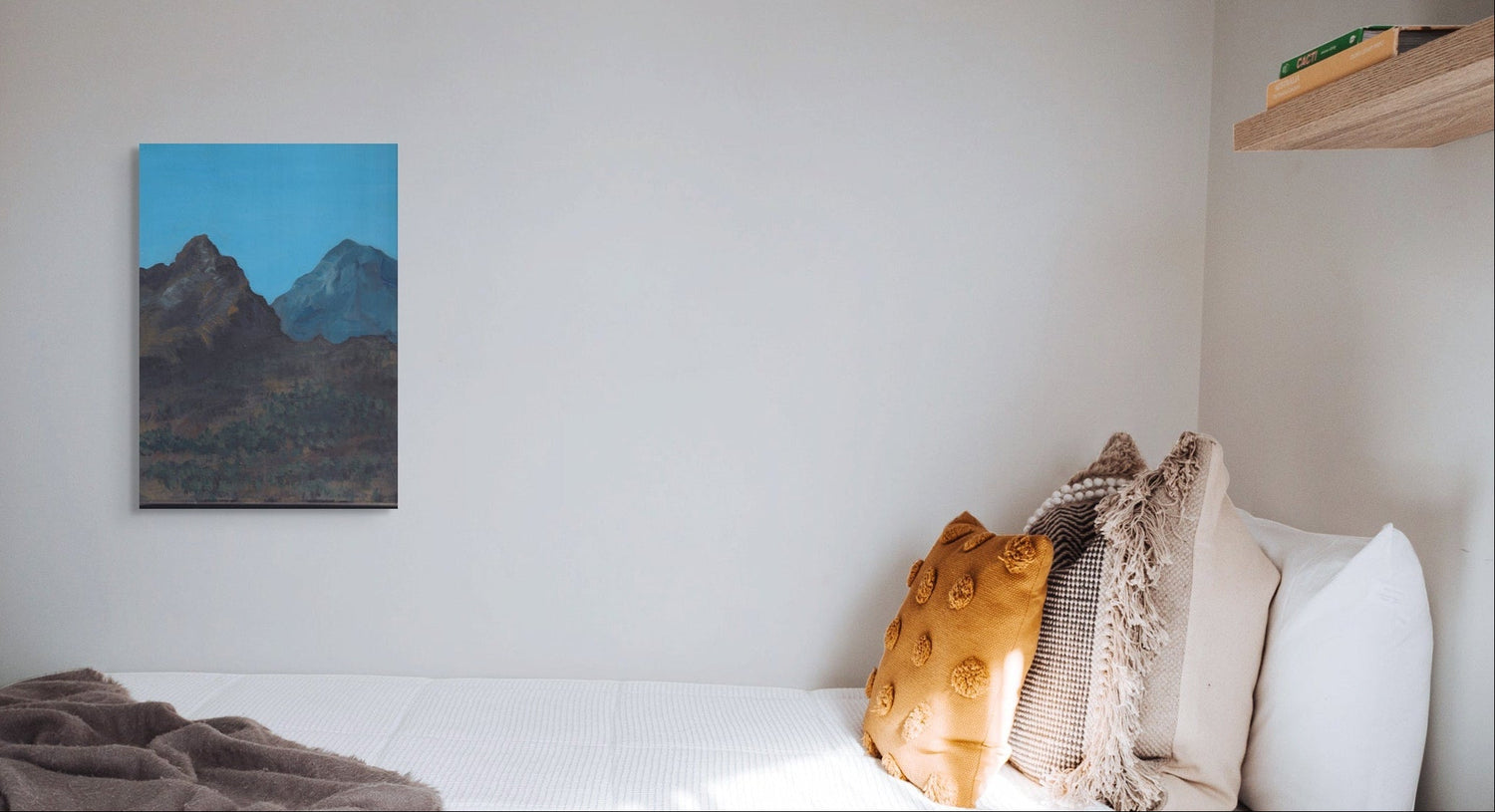 Bedroom with a bed, pillows, and a painting of mountains on the wall.